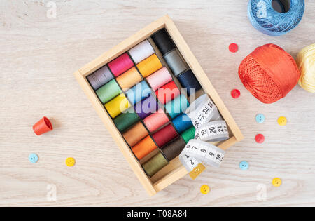 Composition with colorful sewing threads and accessories on wooden background, top view Stock Photo
