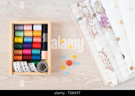 Composition with sewing threads, fabrics and accessories on wooden background, top view Stock Photo
