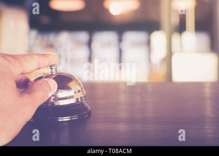 Hand Pressing A Service Bell call service on Hotel Reception Counter Close up Stock Photo