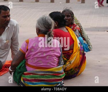 AGRA, UTTAR PRADESH, INDIA--MARCH 2018:  Three women wearing colorful traditional Indian saris and a man sit on the concrete at the Taj Mahal. Stock Photo