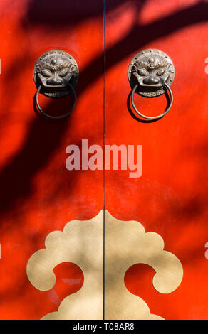 Classical Chinese door knockers with brass lions on traditional red doors Stock Photo