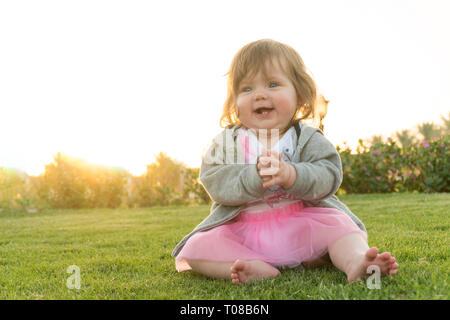 Little funny baby girl sitting on the grass Stock Photo