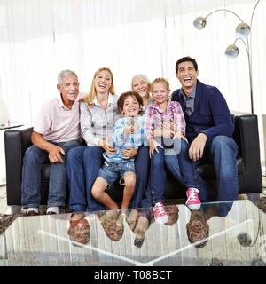 Big happy family is watching TV together in the living room with remote control Stock Photo