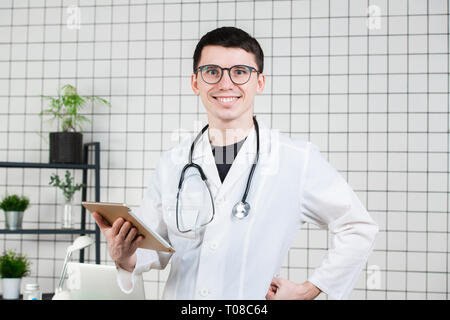 Smiling handsome young male doctor using tablet computer. Technologies in medicine concept Stock Photo