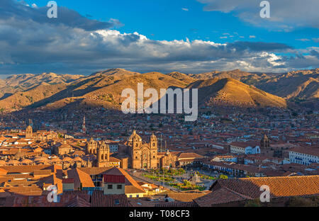 Cityscape of the Plaza de Armas square, Cathedral and Compania de Jesus church, Cusco city at sunset with the Andes mountains in the background, Peru. Stock Photo