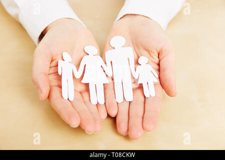 Hands are holding a family with children out of paper Stock Photo