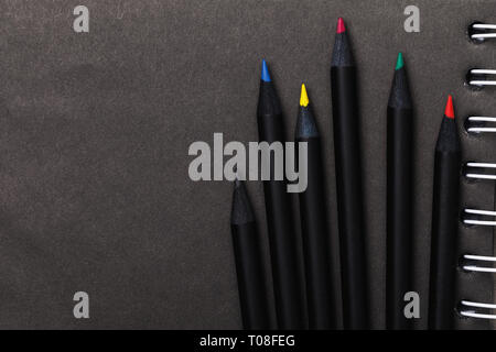 Colored pencils for sketching on black paper with copy space, top view Stock Photo