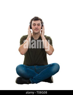 Relaxed casual guy sitting on the floor, legs crossed, listening calming music on headphones, holding hands to ears, being inspired isolated over whit Stock Photo