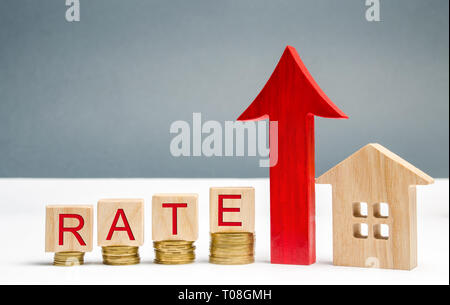 Wooden blocks with the word Rate, up arrow and wooden house. The concept of raising interest rates on mortgages. Growing interest on the loan. Rates a Stock Photo