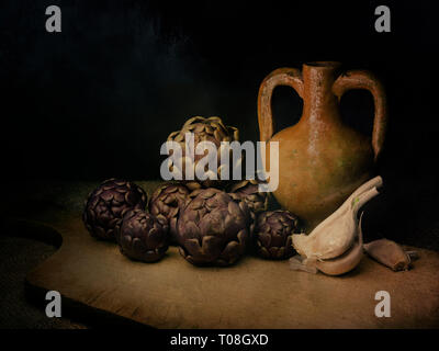 Raw artichokes, Mediterranean vegetable, on rustic hessian with garlic and terracotto amphora urn. Still life, light painting with texture. Artistic. Stock Photo