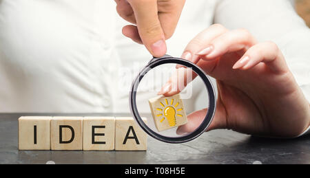 A business woman holding a wooden block with a light bulb idea or inspiration. Generation of innovative business ideas. Creative process. The accumula Stock Photo