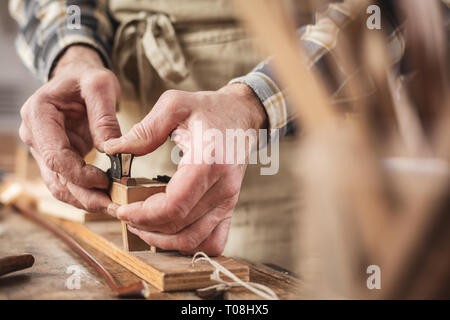 Hands of an instrument maker working on a violin bow Stock Photo