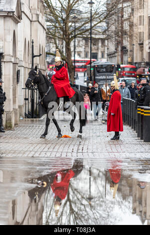 Changing of the Guard mounted ceremony after heavy rain. Reflected in puddle. Life Guards of the Household Cavalry in winter uniform long coats Stock Photo
