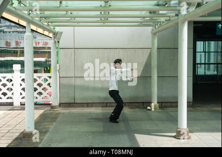 18.04.2018, Singapore, Singapore, Singapore - A man does Tai Chi exercises in a small park outside the People's Park Complex in Singapore's Chinatown  Stock Photo