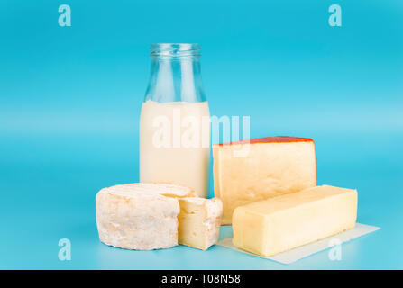 Various fresh dairy products isolated on blue background. Cheese, milk and butter. Stock Photo