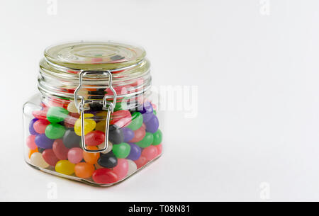 An assortment of jelly beans in a glass jar with clasp lid.  Isolated on white background.  Copy space on right side. Stock Photo
