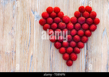 Raspberry berries on a wooden background. Heart of berries on wooden background Stock Photo