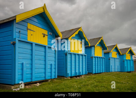 Old wooden beach huts on Felpham greensward on a cloudy Spring day near Bognor Regis, West Sussex, UK Stock Photo