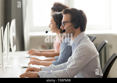 Male call center agent in wireless headset consulting online client Stock Photo