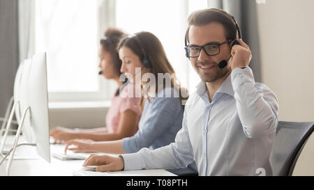 Smiling male call center operator in headset looking at camera Stock Photo