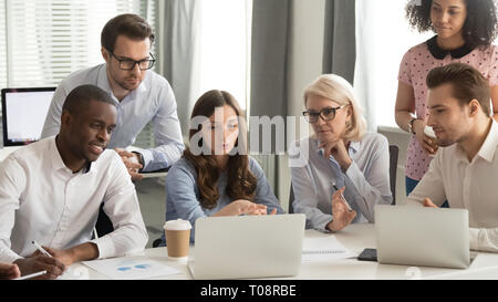 Focused employees group talk working together looking at laptop computer Stock Photo