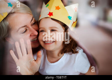 A portrait of small girl with mother having fun at home. Shot through glass. Stock Photo