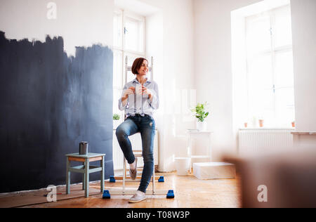 A portrait of young woman painting wall black. A startup of small business. Stock Photo