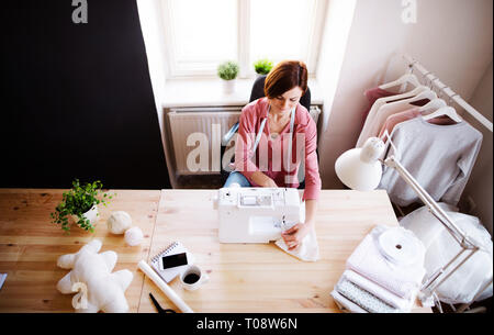 Young creative woman in a studio, working. A startup of tailoring business. Stock Photo