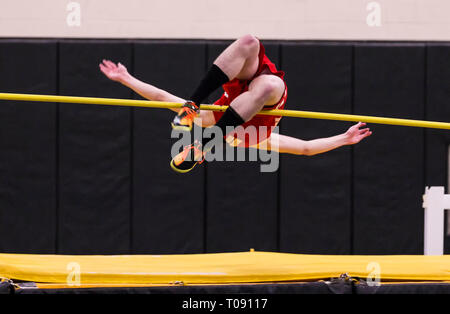 A high school high jumper competing in a track and field event attempting to clear the bar. Stock Photo