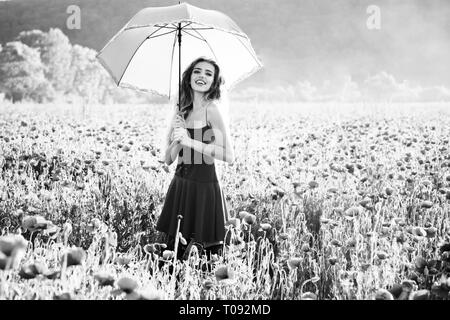 pretty happy girl in field of poppy seed with umbrella Stock Photo