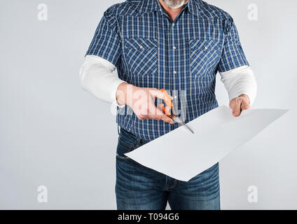 man in blue shirt scissors blank white sheet of paper, studio photo on white background Stock Photo