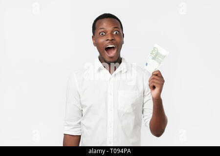 Young rich african american man in shirt holding one hundred euro with surprise Stock Photo