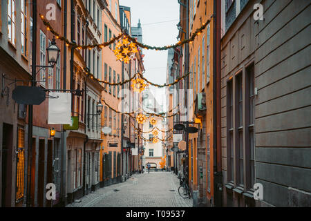 Classic twilight view of tradtional houses in beautiful alleyway in Stockholm's historic Gamla Stan (Old Town) illuminated during blue hour at dusk, c Stock Photo