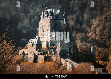Beautiful view of famous Eltz Castle in scenic golden morning light at sunrise with blue sky on a sunny day in fall with retro vintage VSCO style filt Stock Photo