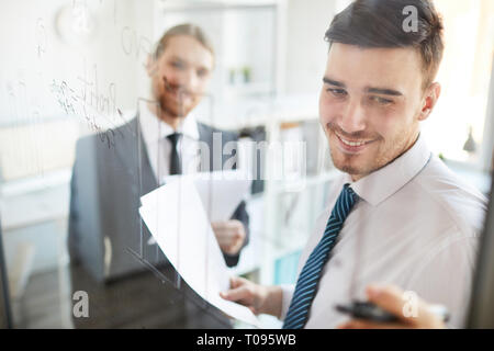 Analyst pointing at data on board Stock Photo