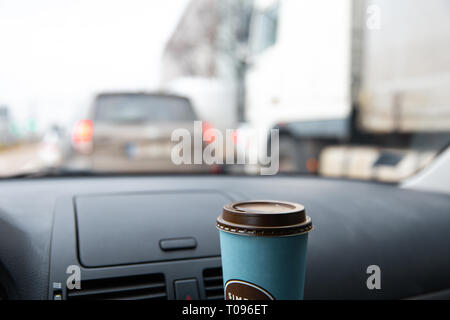 Front window view from inside a car with a blank coffee cup in the evening traffic jam Stock Photo