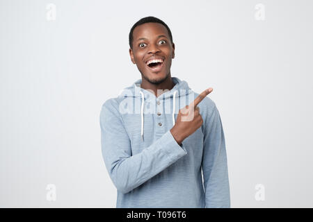 Young african guy smiling and pointing finger aside Stock Photo