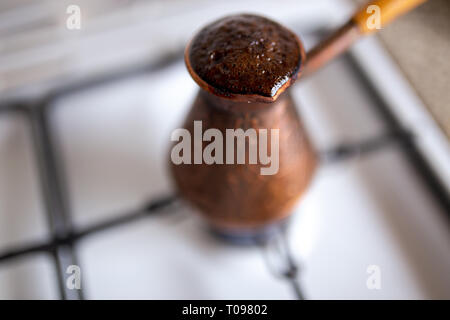 Very hot ready coffee hat - Coffee brewed in a copper cezve on a gas stove in cozy typical kitchen in the morning Stock Photo