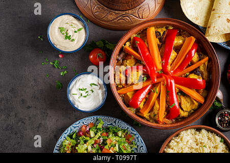 Moroccan food. Traditional tajine dishes, couscous  and fresh salad  on rustic wooden table. Tagine chicken meat and vegetables. Arabian cuisine. Top  Stock Photo