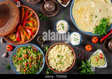 Moroccan food. Traditional tajine dishes, couscous  and fresh salad  on rustic wooden table. Tagine chicken meat and vegetables. Arabian cuisine. Top  Stock Photo