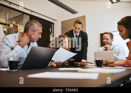Group of diverse businesspeople discussing paperwork while having a meeting together in an office boardroom Stock Photo
