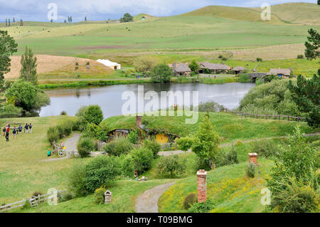 Hobbiton movie set in the Waikato region of New Zealand north island. Rolling hills of The Shire with lake, mill, bridge, Green Dragon Inn. Visitors