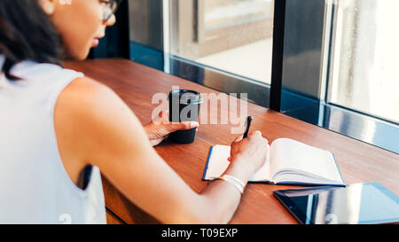 Young entrepreneur taking notes in cafe Stock Photo