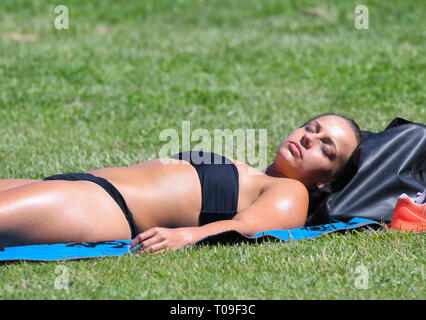 Young pretty woman in he 20's laying on her back on grass sunbathing in Summer in the UK. Stock Photo