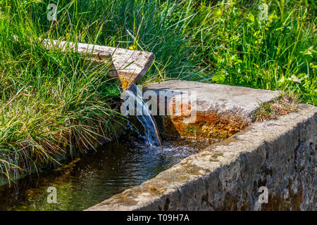 Stone troughs with running clear water from a well Stock Photo