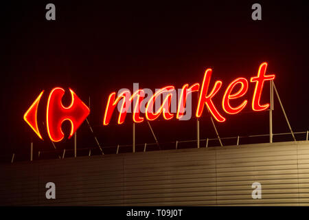 Carrefour French supermarket shop logo & name on display on the front of the shop building in France, during the evening / dusk / night. (104) Stock Photo