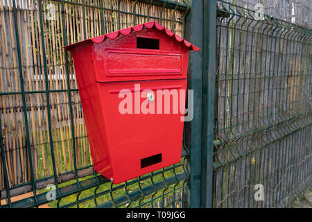 Red mailbox on metallic fence. Outdoor Stock Photo