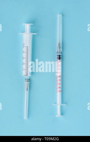 Two syringes on blue background. Making injections using medical equipment of different volume and size. Stock Photo