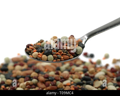 Variety of protein rich colorful legumes on silver spoon with copy space, close up Stock Photo