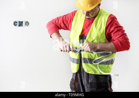 Electrician repairing / fixing wires in the wall. Stock Photo